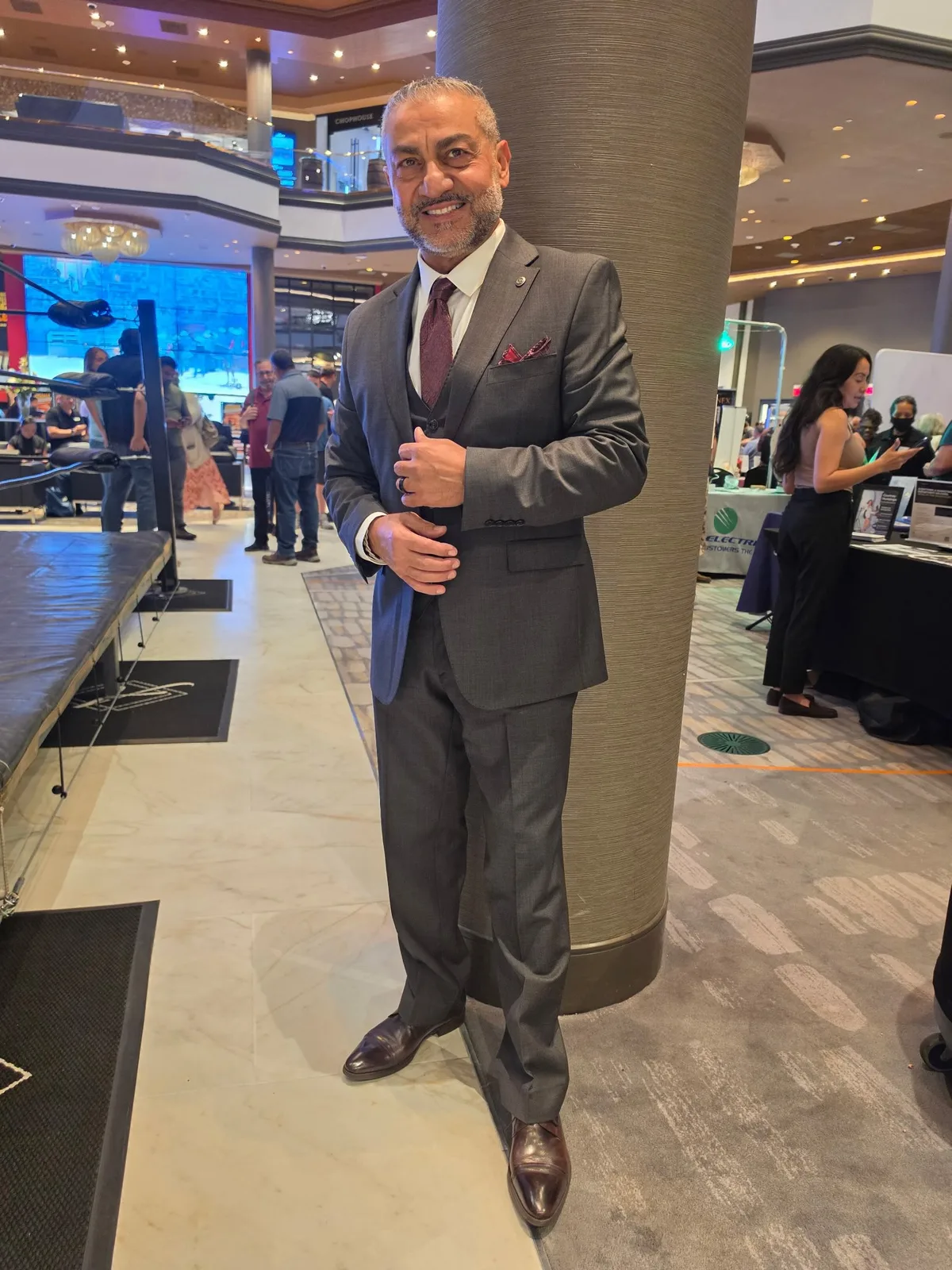 Hombre mayor sonriente con traje beige y corbata marrón