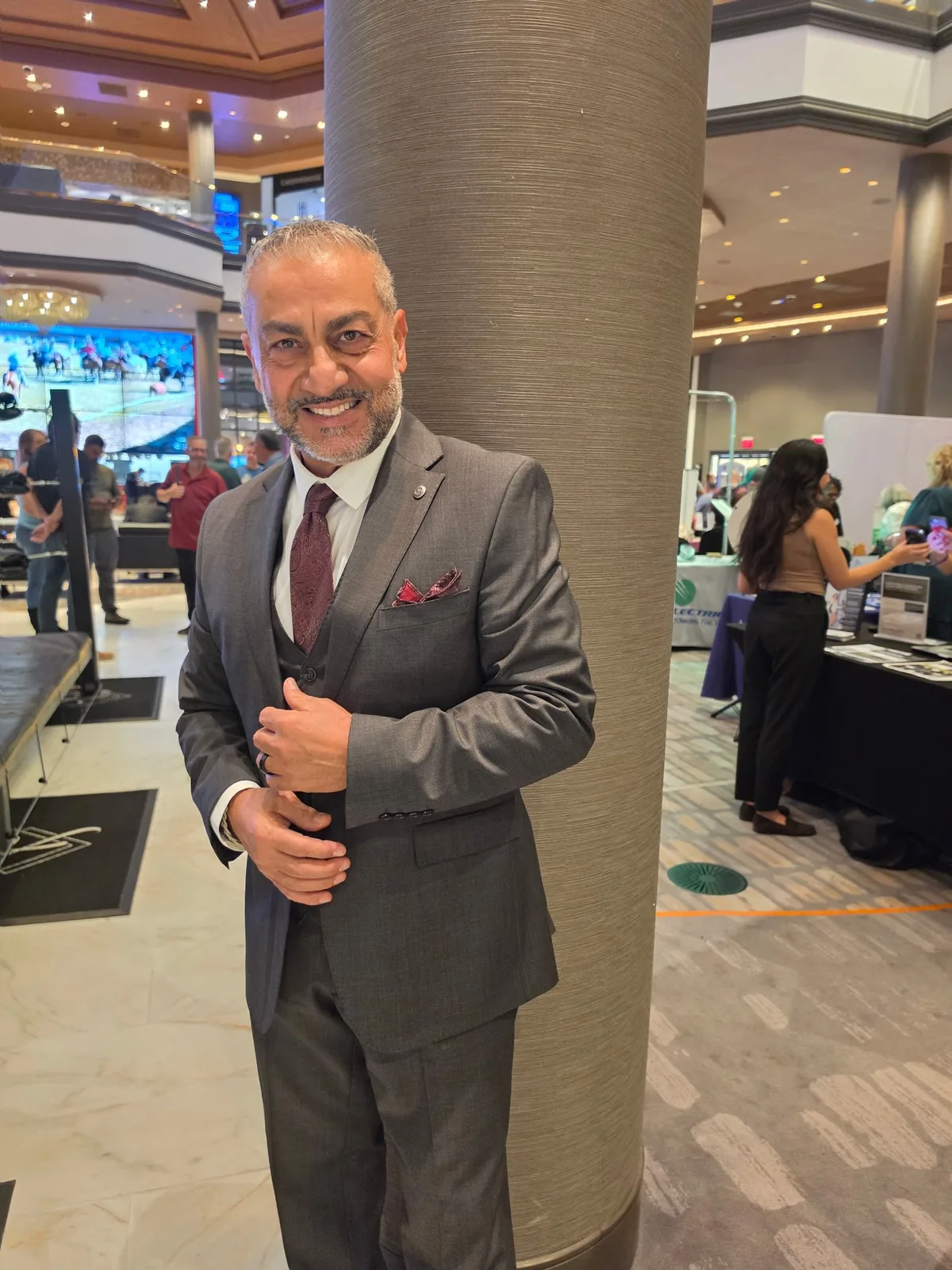 Hombre con traje gris a medida y corbata burdeos en un evento en interior