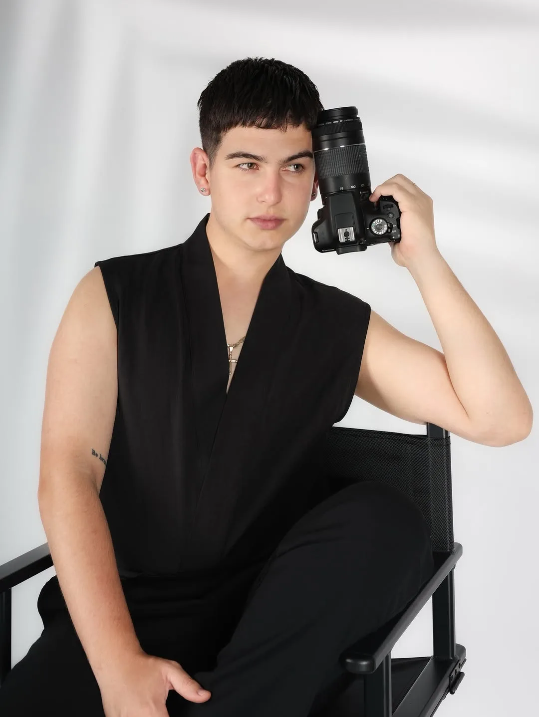 Fotógrafo en atuendo negro sosteniendo su cámara en estudio