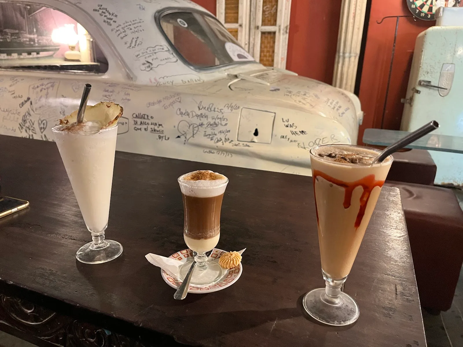 Salón de Café Fortuna Joe en penumbra dorada con auto rojo suspendido y decoración vintage