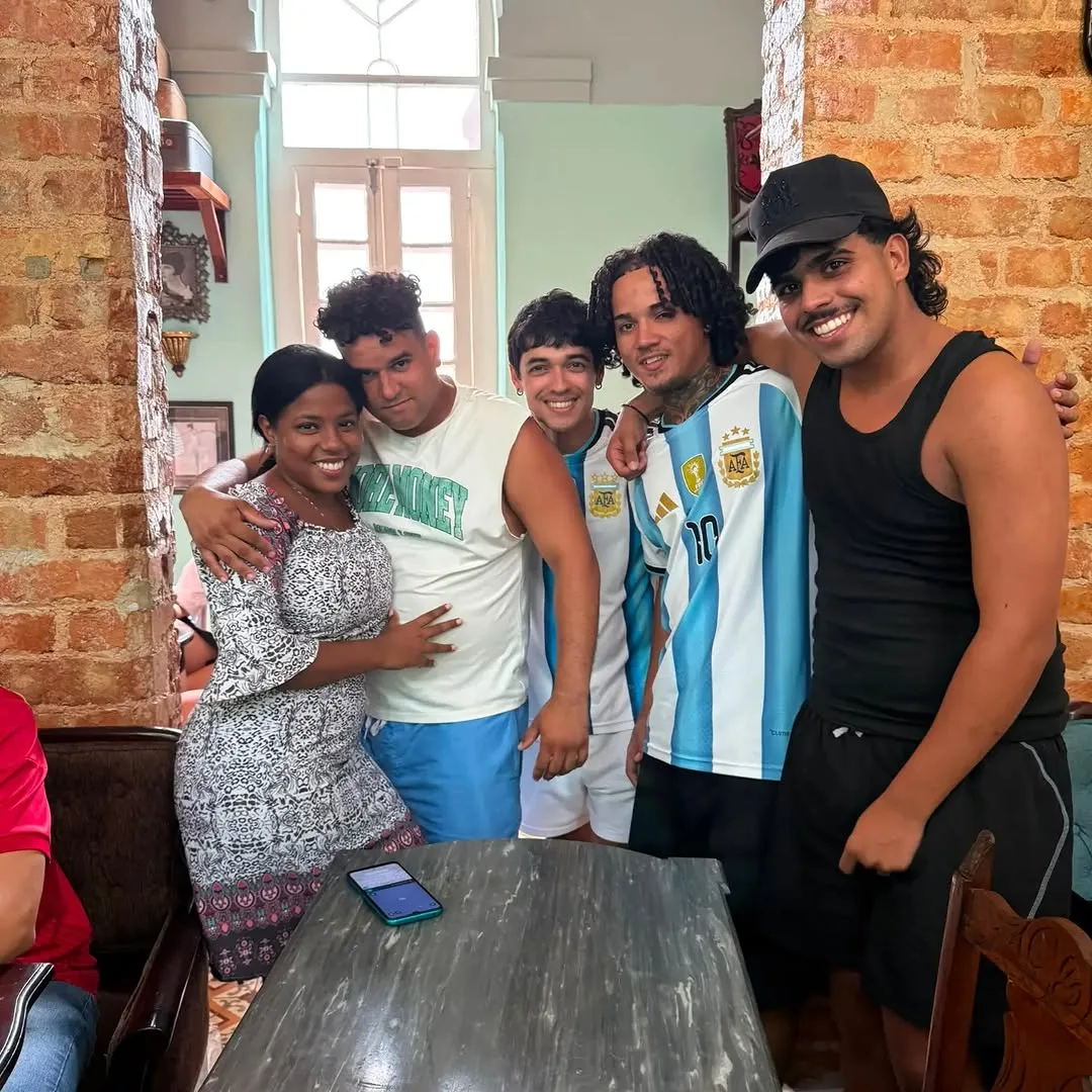 Cinco personas sonriendo en interior vintage con pared de ladrillo